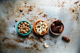 Three small cups, each with a type of nut.