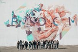 A group of women stand before a wall mural