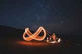 infinity symbol painted by light in the air at a campfire