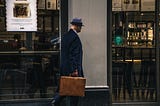 Picture of a spy with a briefcase walking past a bookshop via Alt text on Medium