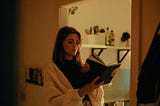 A girl wearing a white cardigan and enjoying her time reading a book