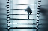 person walking up a glass staircase, view from below