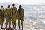 Soldiers looking over a city from a mountain.