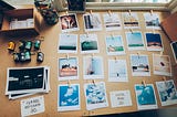 A table beside a window full of colourful polaroid print-outs laid out in a rectangular formation