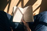 Reading a book sitting cross-legged on the floor