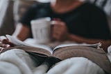 close up of man drinking coffee and reading in bed