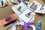Many notebooks open on a table showing surreal doodles and cut up art