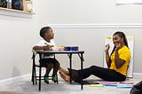 A happy primary-elementary boy doing homework with his mother