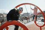Image of two children climbing on a playground wearing winter clothes.