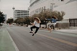 2 girls jumping in the air in the middle of the road