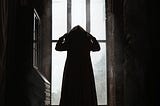 Cloaked silhouette in some sort of olde timey building like a castle or a church