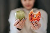 A lady showing a picture of apple and a donut.