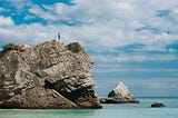 swimmer standing at top of cliff beside the ocean