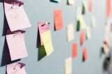 A blue bulletin board covered in colorful sticky notes.