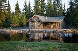 A beautiful villa surrounded by a forest facing a lake with birds playing