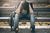 A man sitting on a bench with his head down