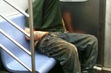 This is an image of a man with his shirt pulled up over his face to give him privacy while his hand is in his pants in this public location. His butt cheeks are absolutely touching the seat. There is sweat there. Between his butt cheeks.