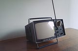 Vintage portable television sitting on table | When Therapy Wasn’t an Option, I Found Morning TV | Live television taught me what children’s shows could not | Nikki Abelson