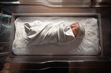 A newborn baby swaddled in a hospital infant bed