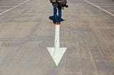 Person standing in front of an arrow pointing backwards