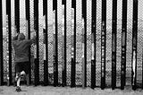 A man leaning on the border fence.