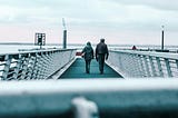 A couple is walking on a boardwalk