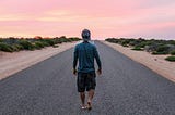 person walking alone down an empty road