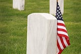 Mickey Markoff Air Sea Exec 2024 — Grey gravestone with American flag in green grass posted on mickey markoff article on the net worth of legacy and paying tribute to veterans