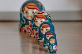 Painted nesting dolls lined up, smallest one in front, largest in back