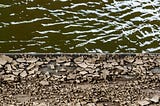 On the top half, green flowing river water, and on the bottom, fractured rock.