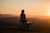 person sitting on a bench at sunset