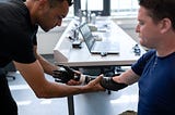 A man in a wheelchair having a prosthetic lower arm fitted by a prosthetist