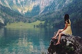 A woman looking at the mountain reflecting back.