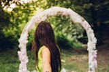 Woman reaching back holding hand of partner and looking toward wedding altar