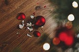 A single red Christmass light, or decor, that’s broken and on the floor. Depicts the idea of breaking after shining too bright for others.
