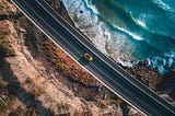 aerial photo of car driving on a highway next to the ocean