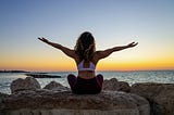 Woman at the beach with a yoga pose to make her day feel better