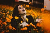 woman in a field of flowers, laughing to the skies