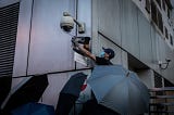 A protester covers a camera outside a government office in Hong Kong after protests on Chinese AI-led surveillance in 2019