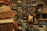 Young woman looking at a very overflowing and cluttered bookshelf