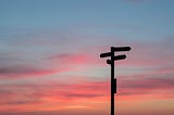 A sign post pointing in four directions at sunset