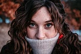 Woman with the neck of a jumper covering her mouth