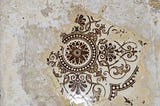 An ornate patterned tile emerging underneath layers of paint