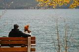 A couple sitting on a bench overlooking the lake.