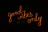 The words good vibes only lit up in orange on a black background.