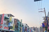 The view of Taiwan street: the shops, the road, the vehicles, and the beautiful evening sky.