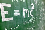 A green blackboard with a number of mathematical formulae written on it.