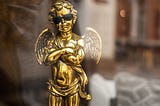 Trophy in the shape of a cherub figurine, folding its arms and wearing sunglasses