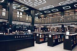 Biblioteca na cor branca, com estantes na cor preta.