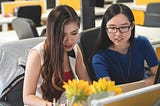 Two female professionals looking at a computer